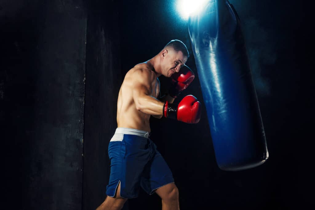 male boxer boxing punching bag with dramatic edgy lighting