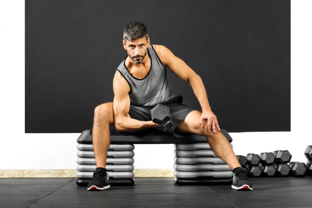 fit man doing curls with dumbbell gym